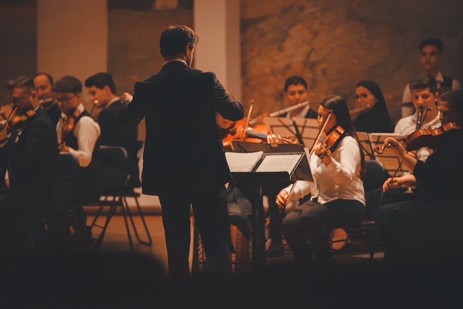 An image showing a conductor leading an orchestra, representing the unheard heroes of the music industry.